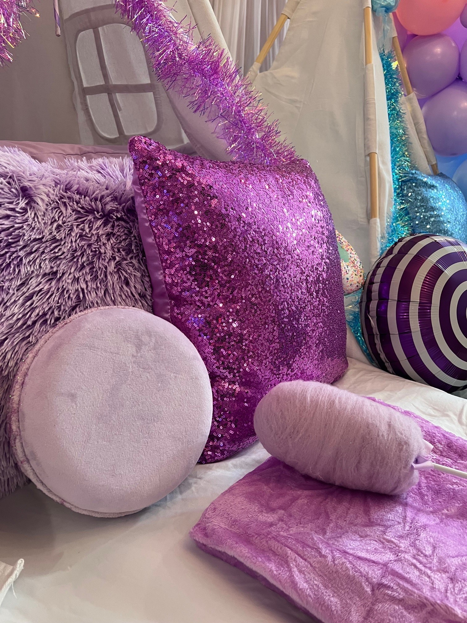 Luxury Candy Land Sleepover setup featuring plush purple pillows, glittery sequins, and cotton candy decorations for a kids’ party in Denver.