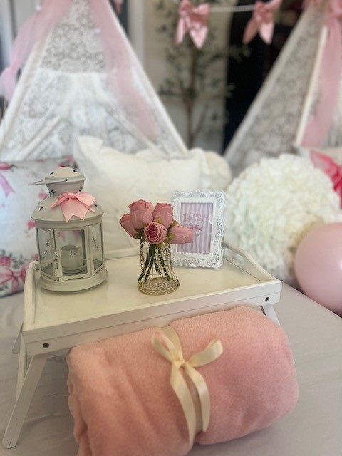 Close-up of a LoveShackFancy-inspired sleepover setup featuring a delicate floral-print teepee, soft pastel pillows, lace accents, and a charming boho aesthetic. The details exude vintage luxury and elegance.