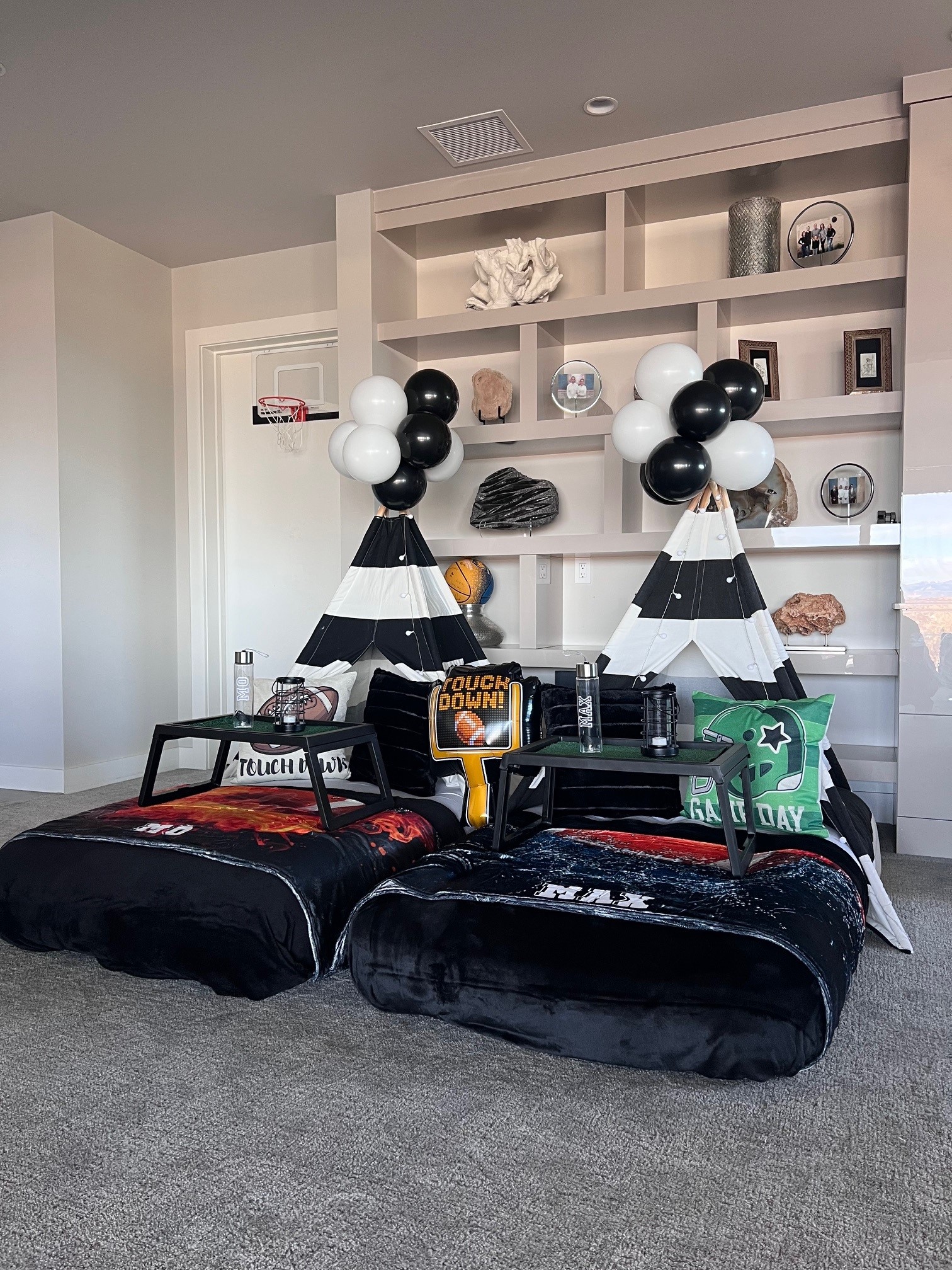 Wide-angle shot of a football-themed sleepover setup with multiple teepees, personalized blankets, custom water bottles, football-themed balloons, and festive decor.