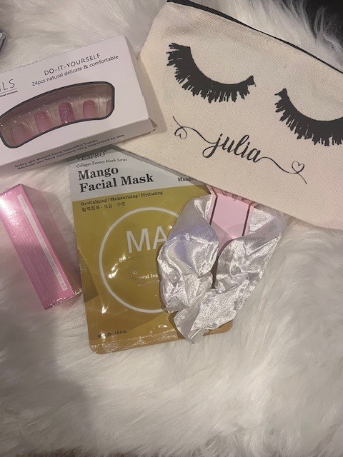 Close-up of a personalized glamour bag filled with party essentials including nails, a face mask, a hair scrunchie, a nail file, and lip gloss.